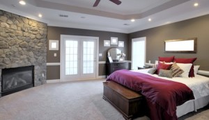 Interior of a large modern bedroom with a fireplace and ceiling fan. Horizontal format.